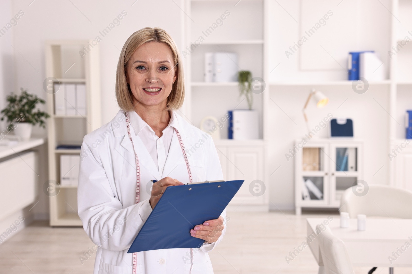 Photo of Weight loss. Smiling nutritionist with clipboard in clinic, space for text