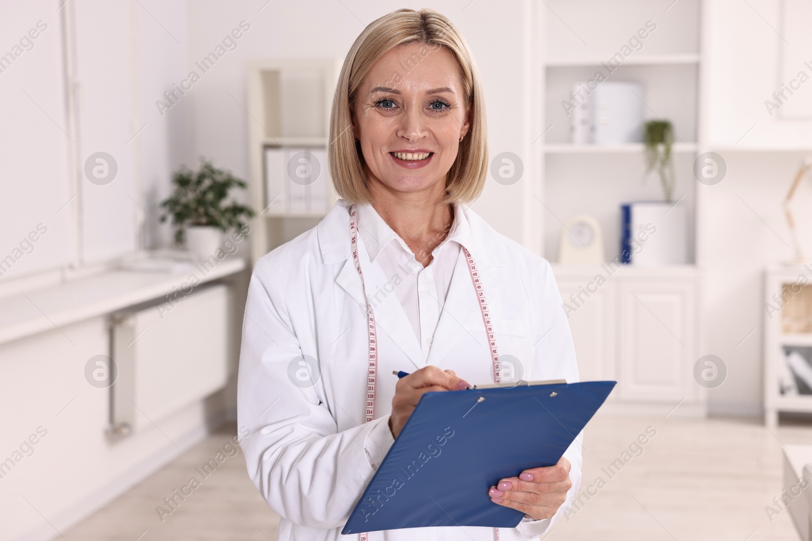 Photo of Weight loss. Smiling nutritionist with clipboard in clinic