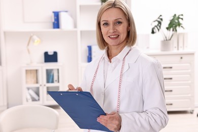 Photo of Weight loss. Smiling nutritionist with clipboard in clinic