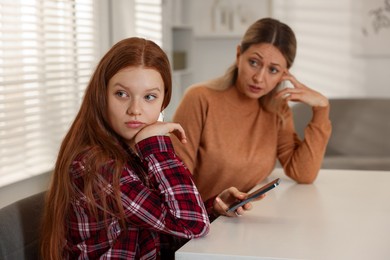 Photo of Annoyed teenage girl with smartphone and her mother at psychologist's office, selective focus