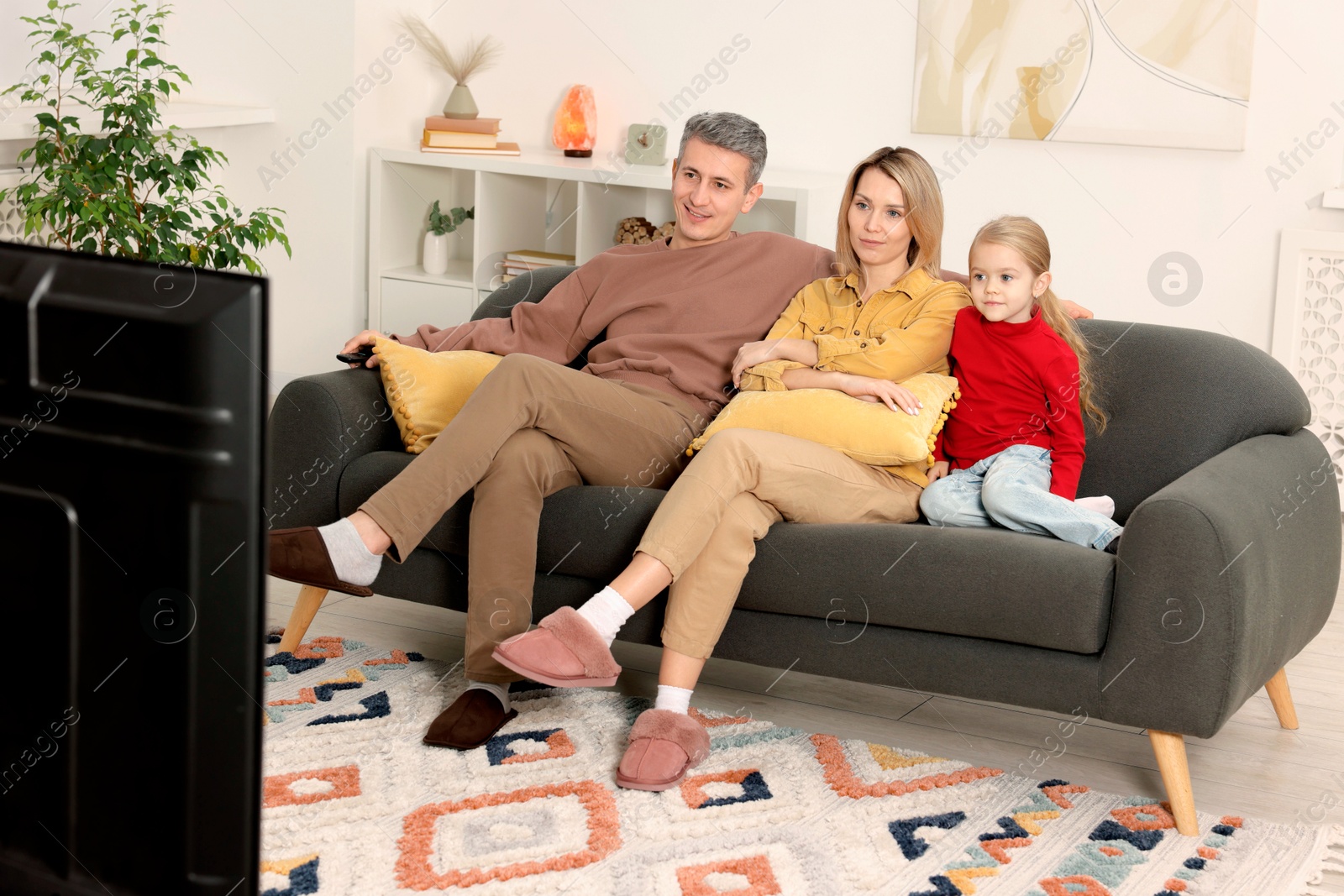 Photo of Family watching TV on sofa at home