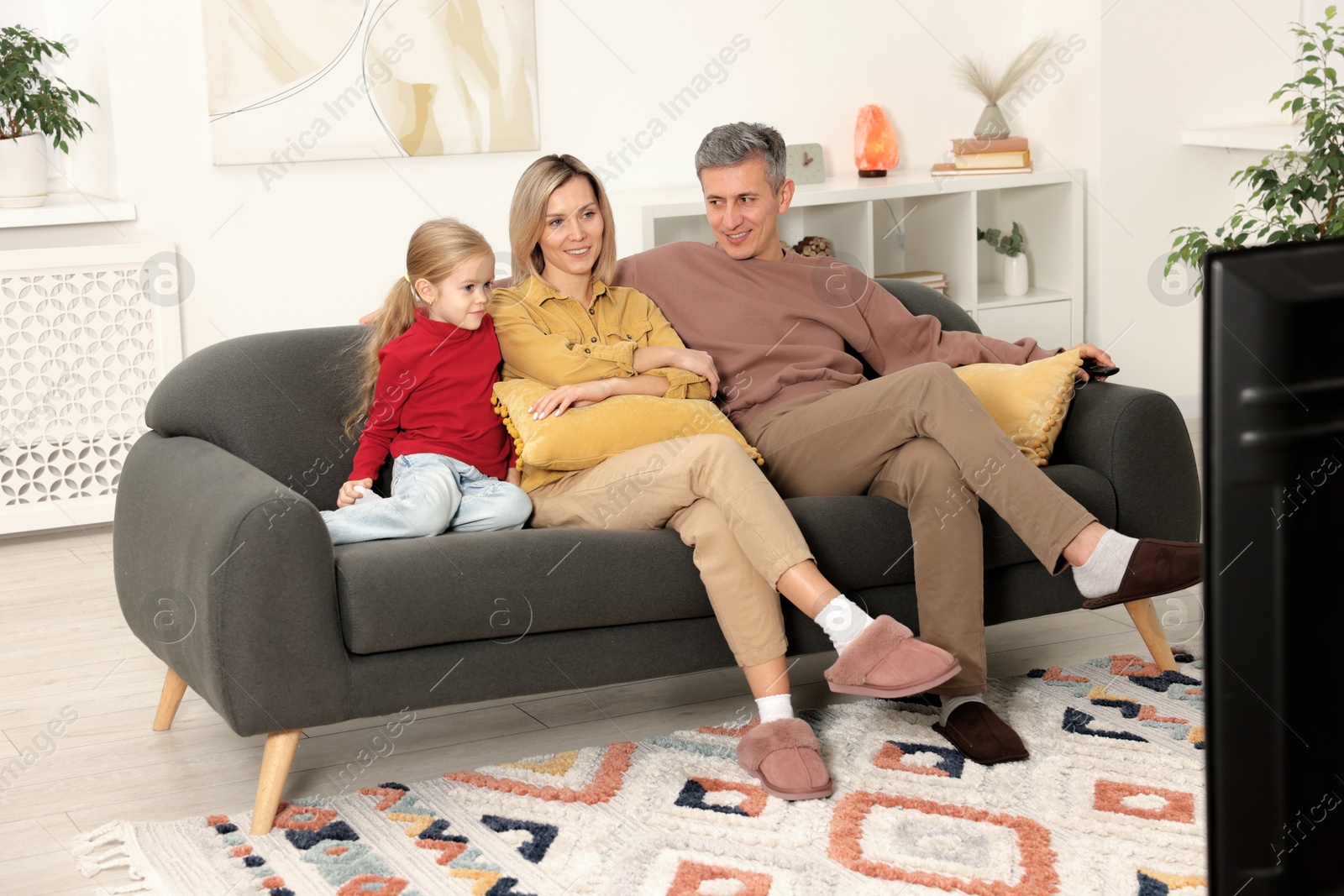 Photo of Family watching TV on sofa at home