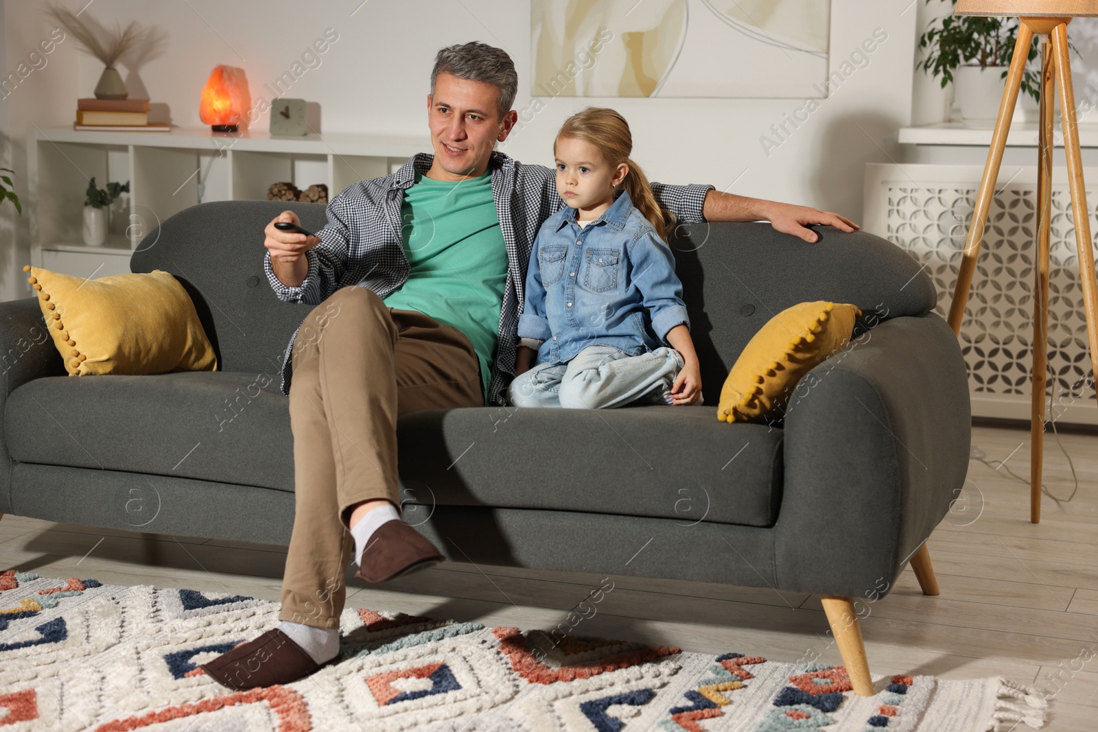 Photo of Father and his daughter watching TV on sofa at home