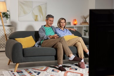 Photo of Lovely couple watching TV on sofa at home