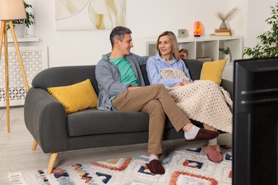 Photo of Lovely couple watching TV on sofa at home