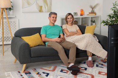 Photo of Lovely couple watching TV on sofa at home