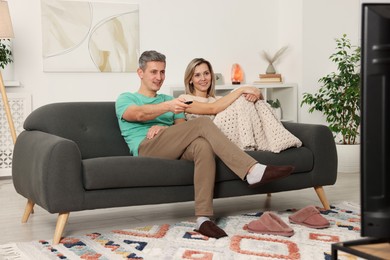 Photo of Lovely couple watching TV on sofa at home