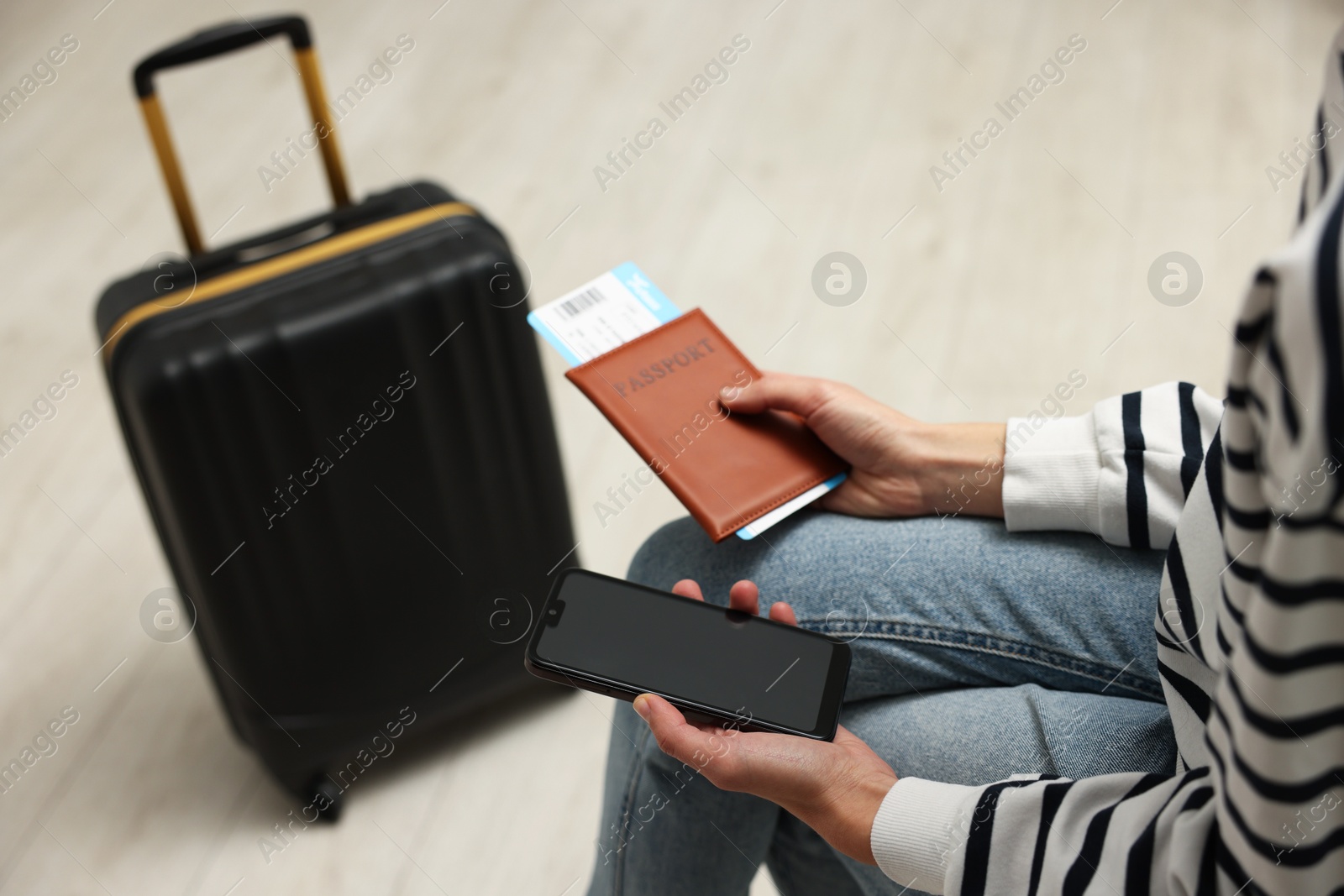 Photo of Traveller with passport, flight ticket and smartphone indoors, closeup