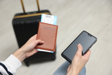 Photo of Traveller with passport, flight ticket and smartphone indoors, closeup