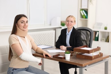 Photo of Injured woman and lawyer at table in office, selective focus