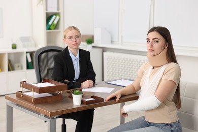 Photo of Injured woman and lawyer at table in office, selective focus