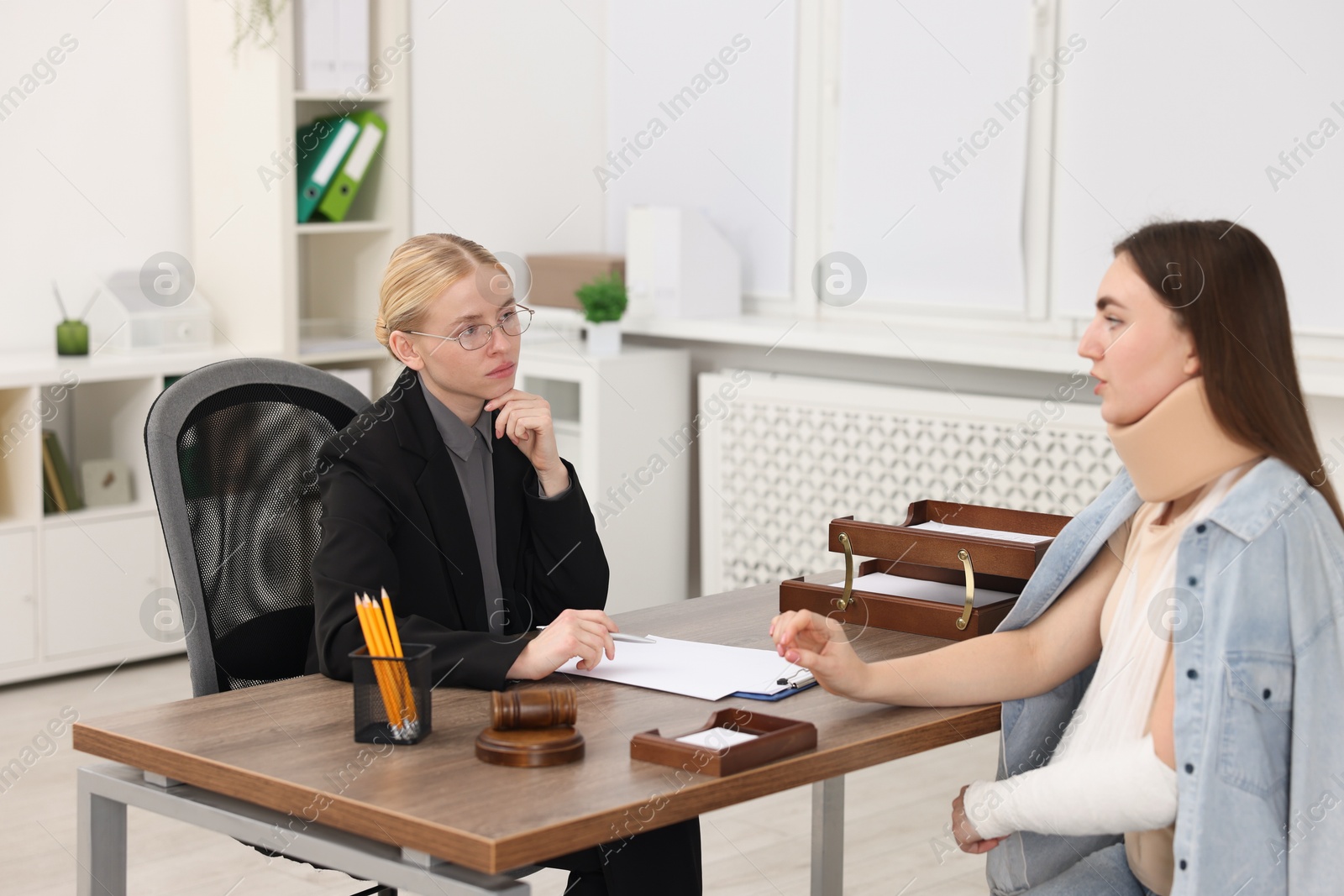 Photo of Injured woman having meeting with lawyer in office, selective focus