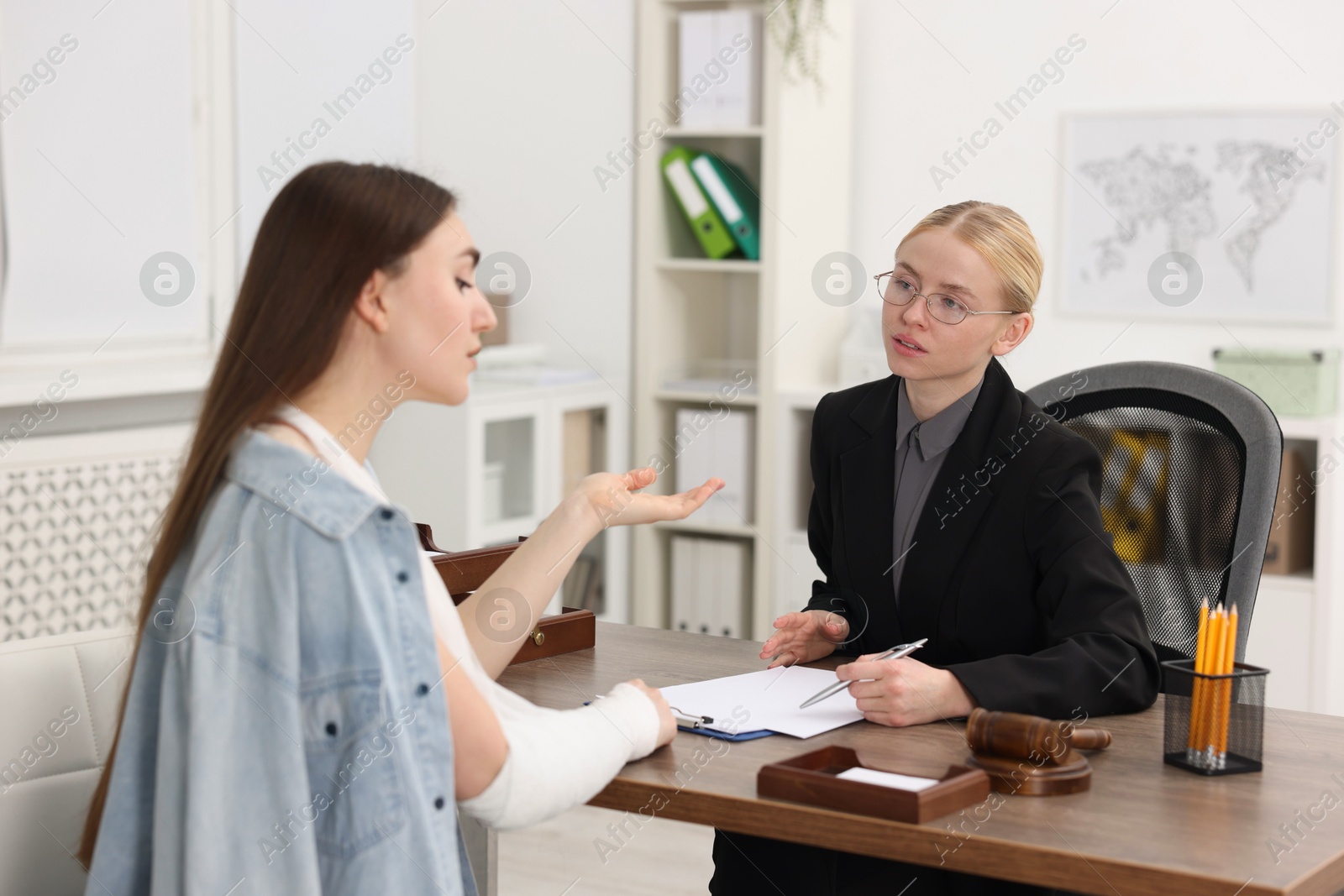 Photo of Injured woman having meeting with lawyer in office, selective focus