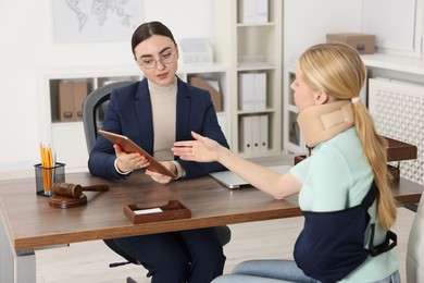 Photo of Injured woman having meeting with lawyer in office, selective focus