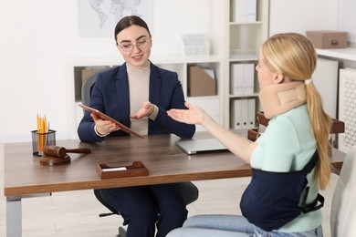 Photo of Injured woman having meeting with lawyer in office, selective focus