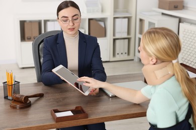 Photo of Injured woman having meeting with lawyer in office, selective focus