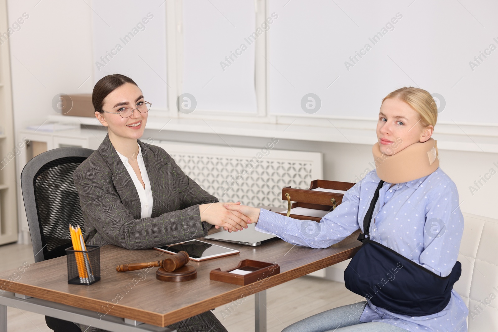 Photo of Injured woman and lawyer shaking hands in office