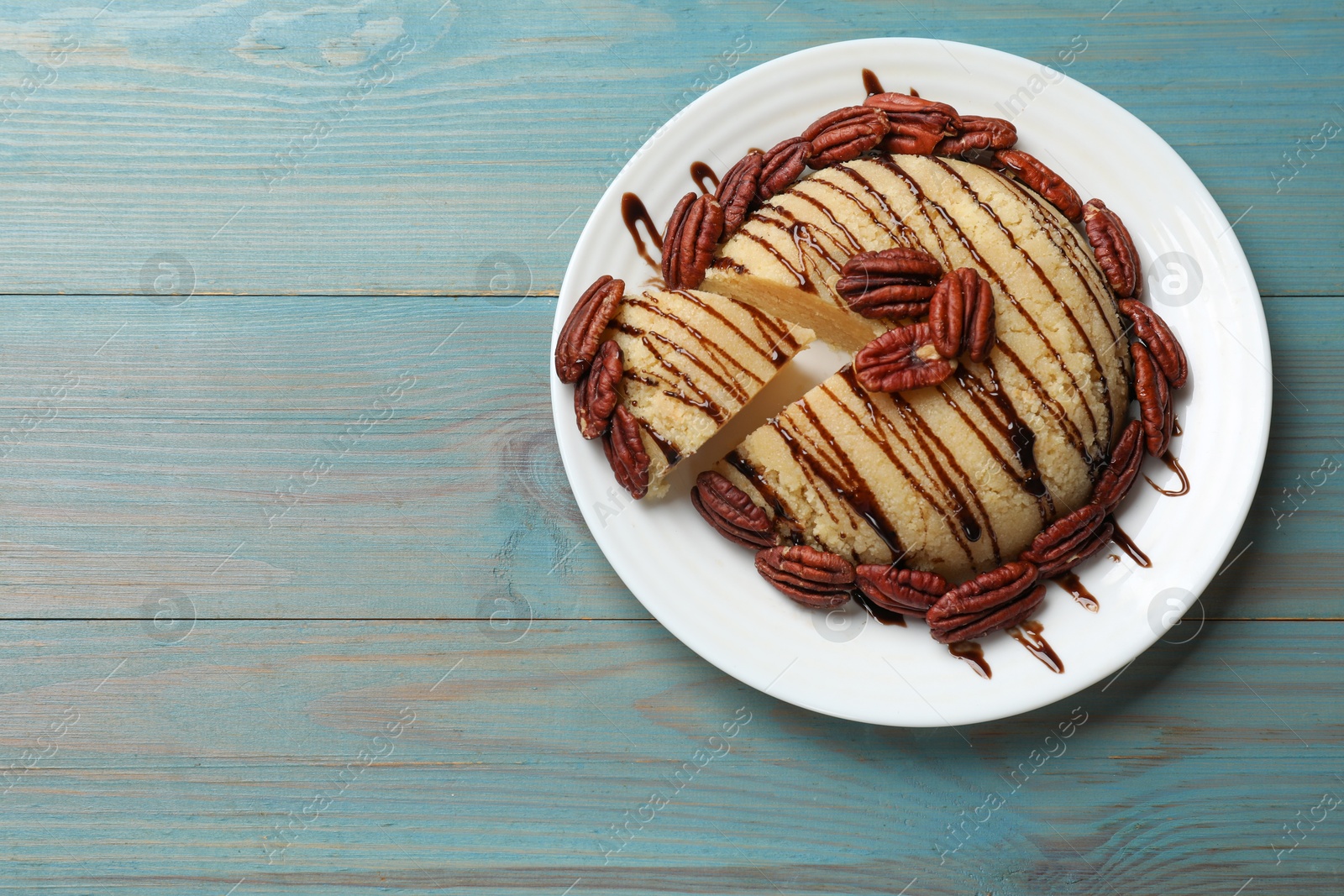 Photo of Delicious sweet semolina halva with pecans on blue wooden table, top view. Space for text