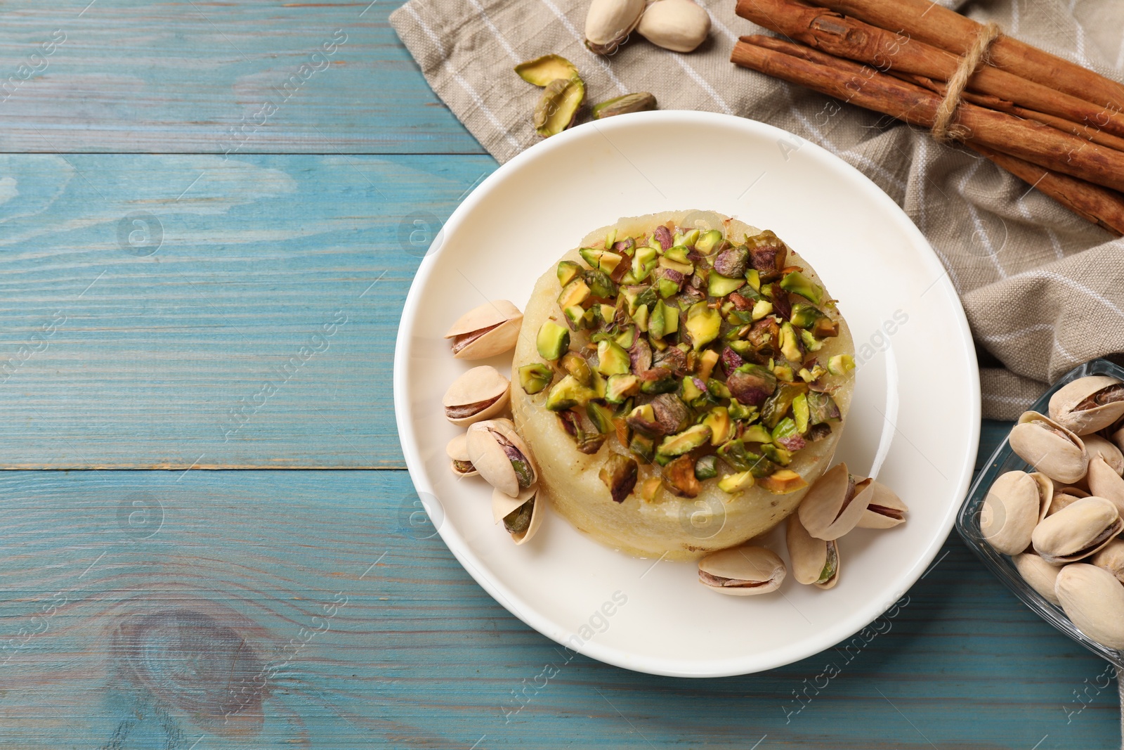 Photo of Delicious sweet semolina halva with pistachios on blue wooden table, flat lay. Space for text