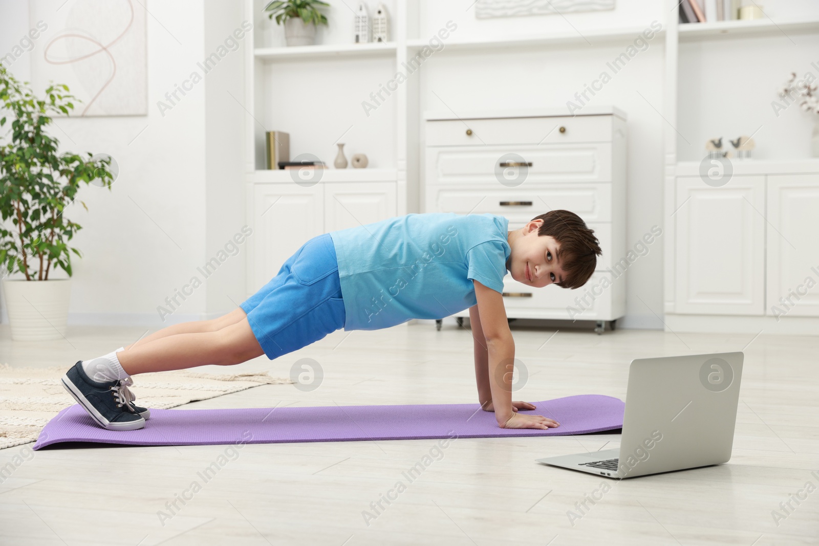 Photo of Boy having training with online coach via laptop at home