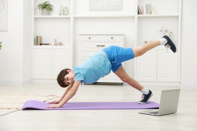 Photo of Boy having training with online coach via laptop at home