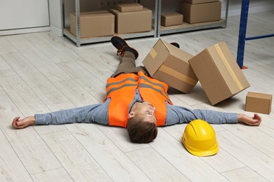 Photo of Accident at work. Unconscious man lying on floor in warehouse