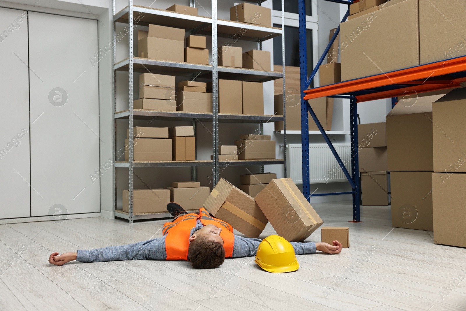 Photo of Accident at work. Unconscious man lying on floor in warehouse