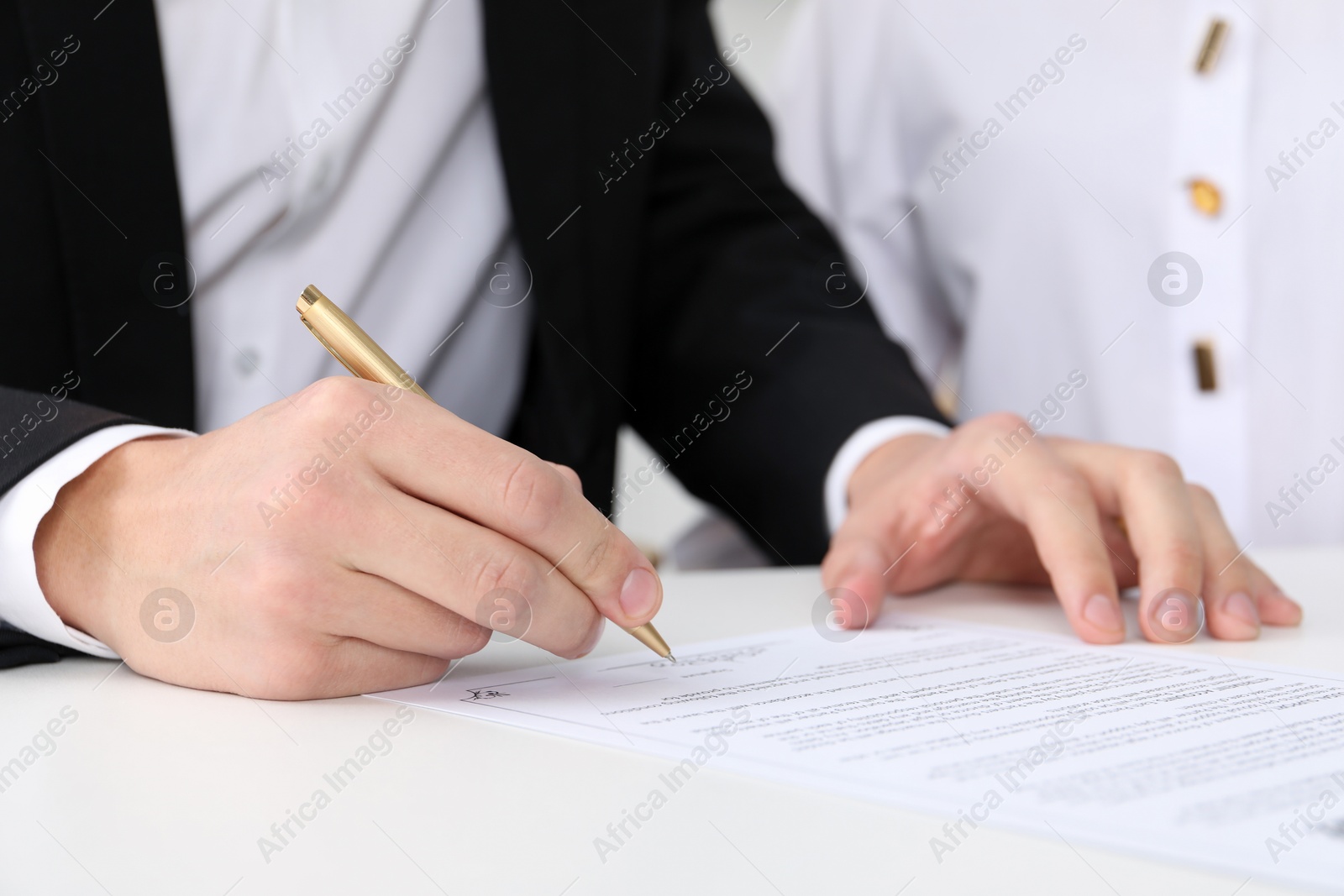 Photo of Newlyweds signing marriage contract at desk, closeup