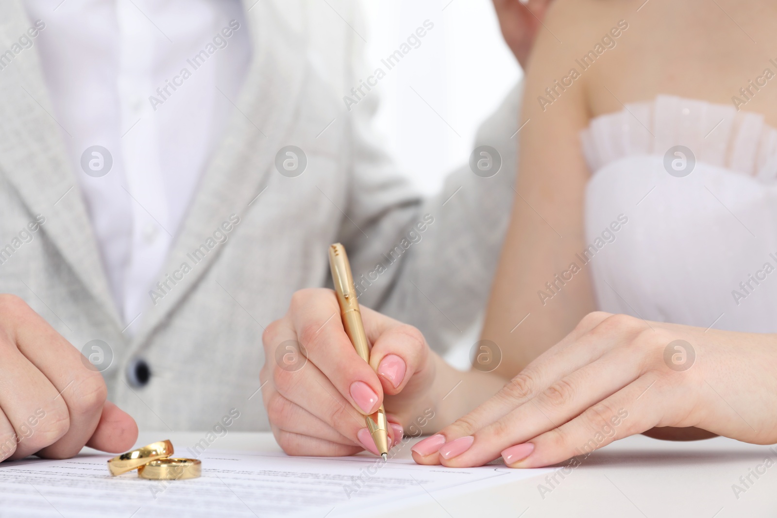 Photo of Newlyweds signing marriage contract and wedding rings on desk, selective focus