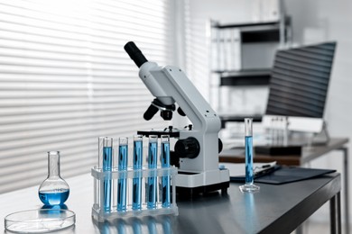 Photo of Chemical glassware and microscope on table in laboratory