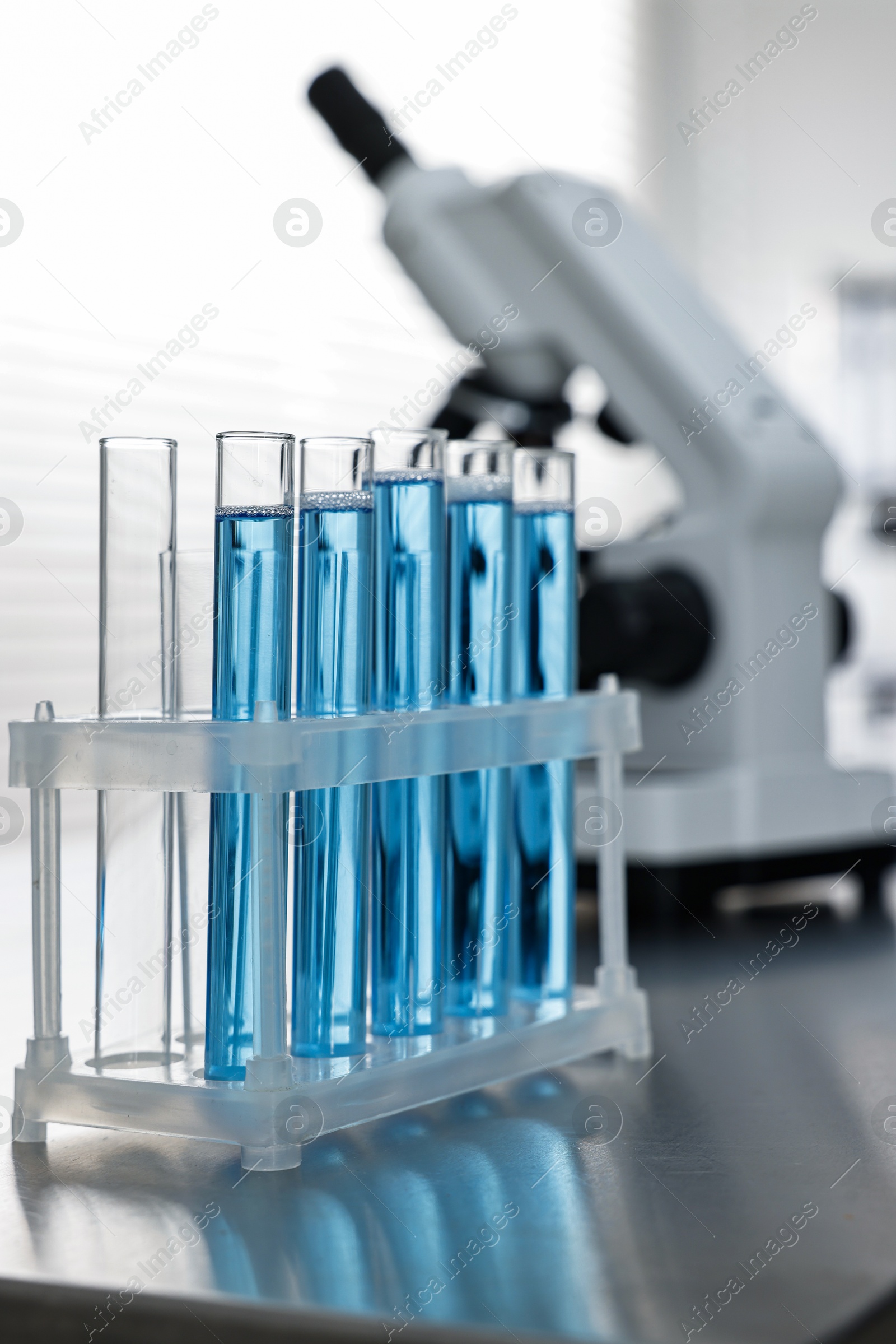 Photo of Test tubes with blue liquid on table in laboratory, closeup