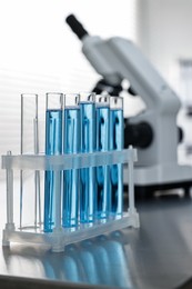 Photo of Test tubes with blue liquid on table in laboratory, closeup