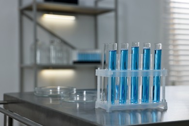 Photo of Test tubes with blue liquid on table in laboratory. Space for text