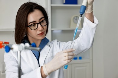 Photo of Scientist with micropipette and test tube working in laboratory