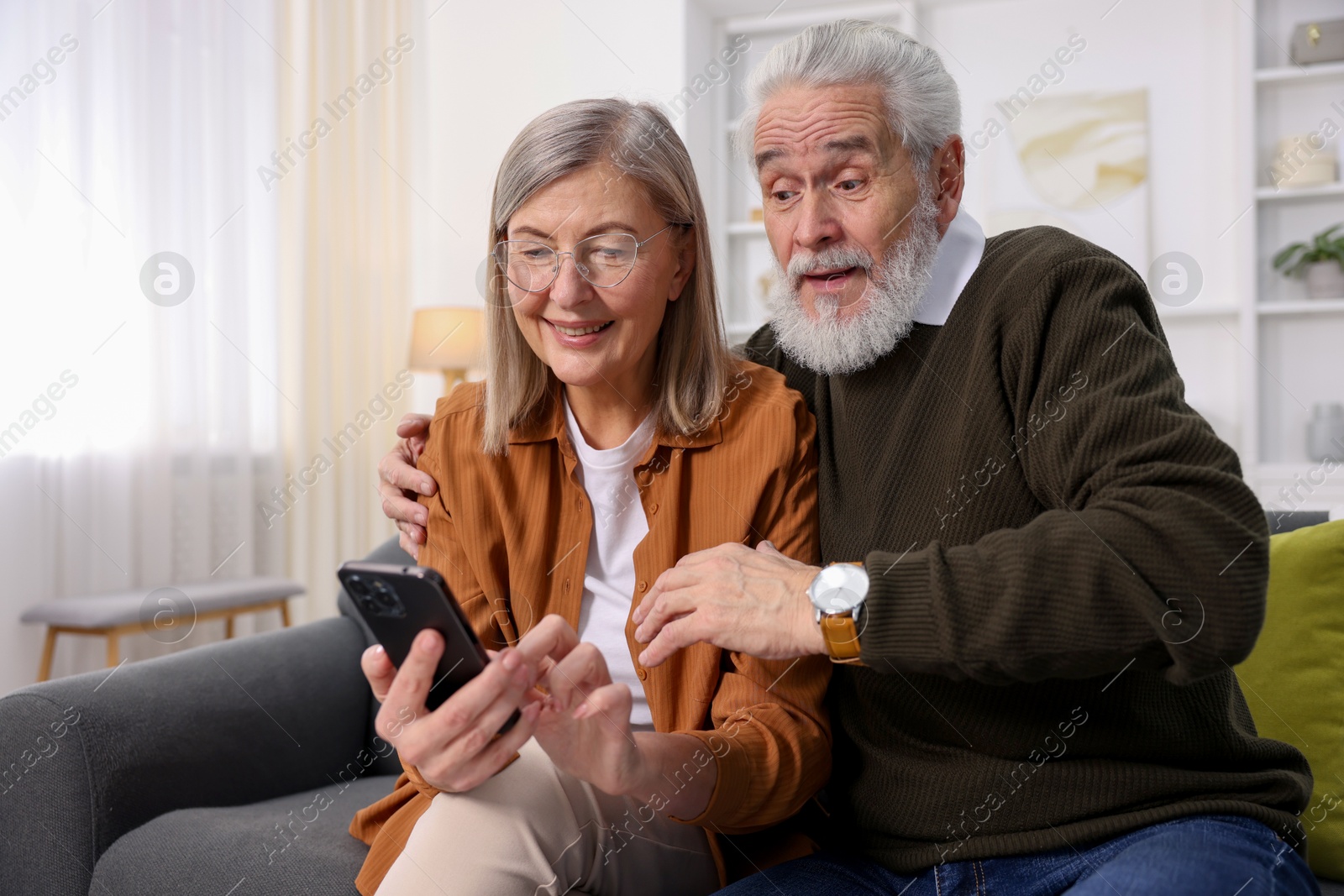 Photo of Cute elderly couple with smartphone on sofa at home