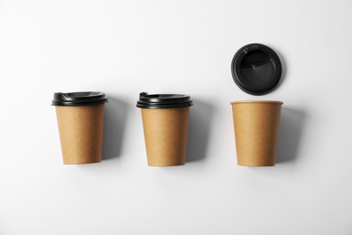 Photo of Paper cups with lids on white background, flat lay. Mockup for design