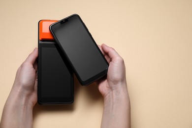 Photo of Woman with smartphone using payment terminal on beige background, top view. Space for text