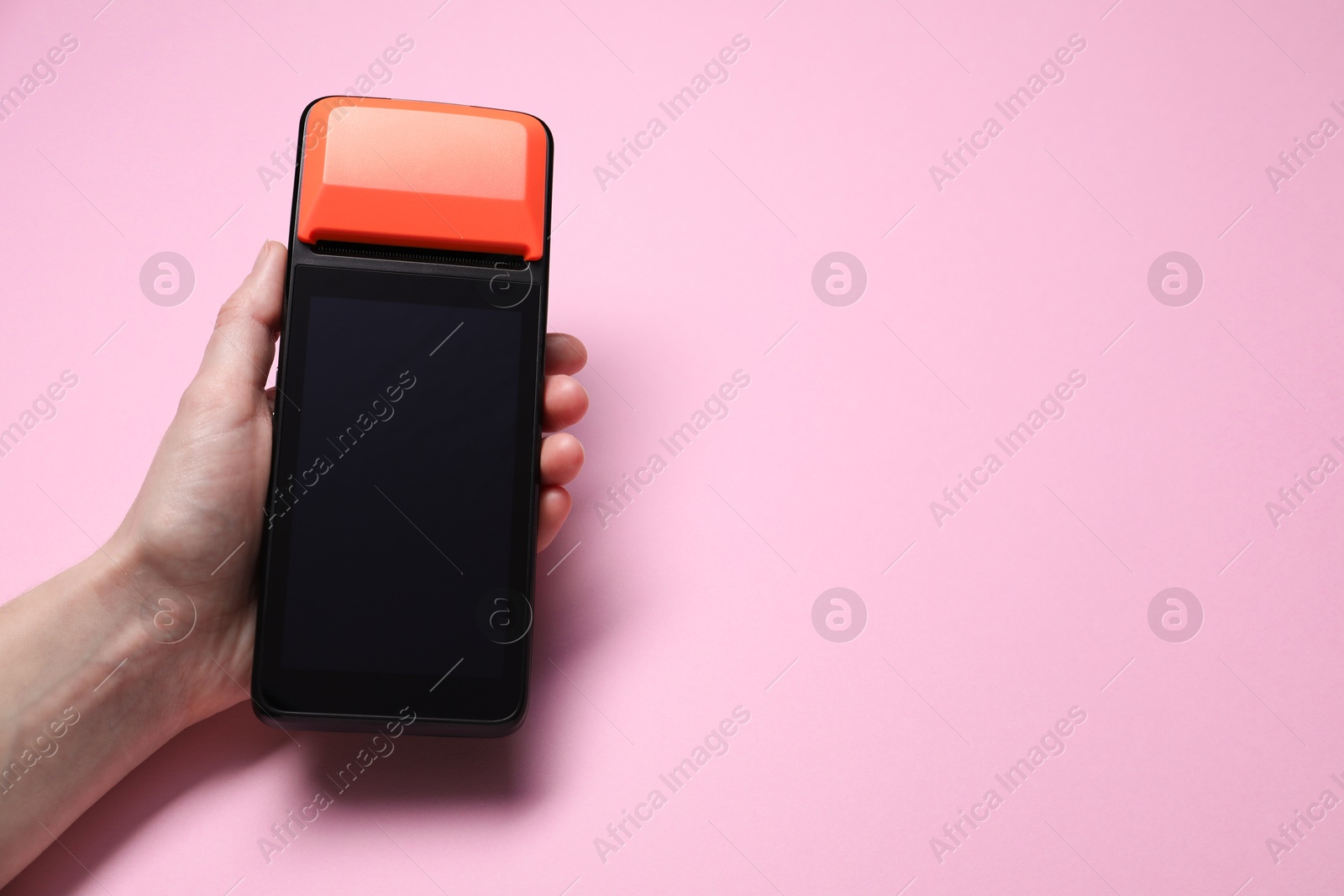 Photo of Woman with payment terminal on pink background, closeup. Space for text