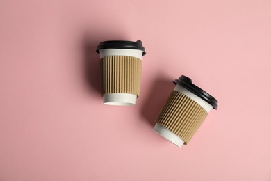 Photo of Paper cups with lids on pink background, flat lay. Mockup for design