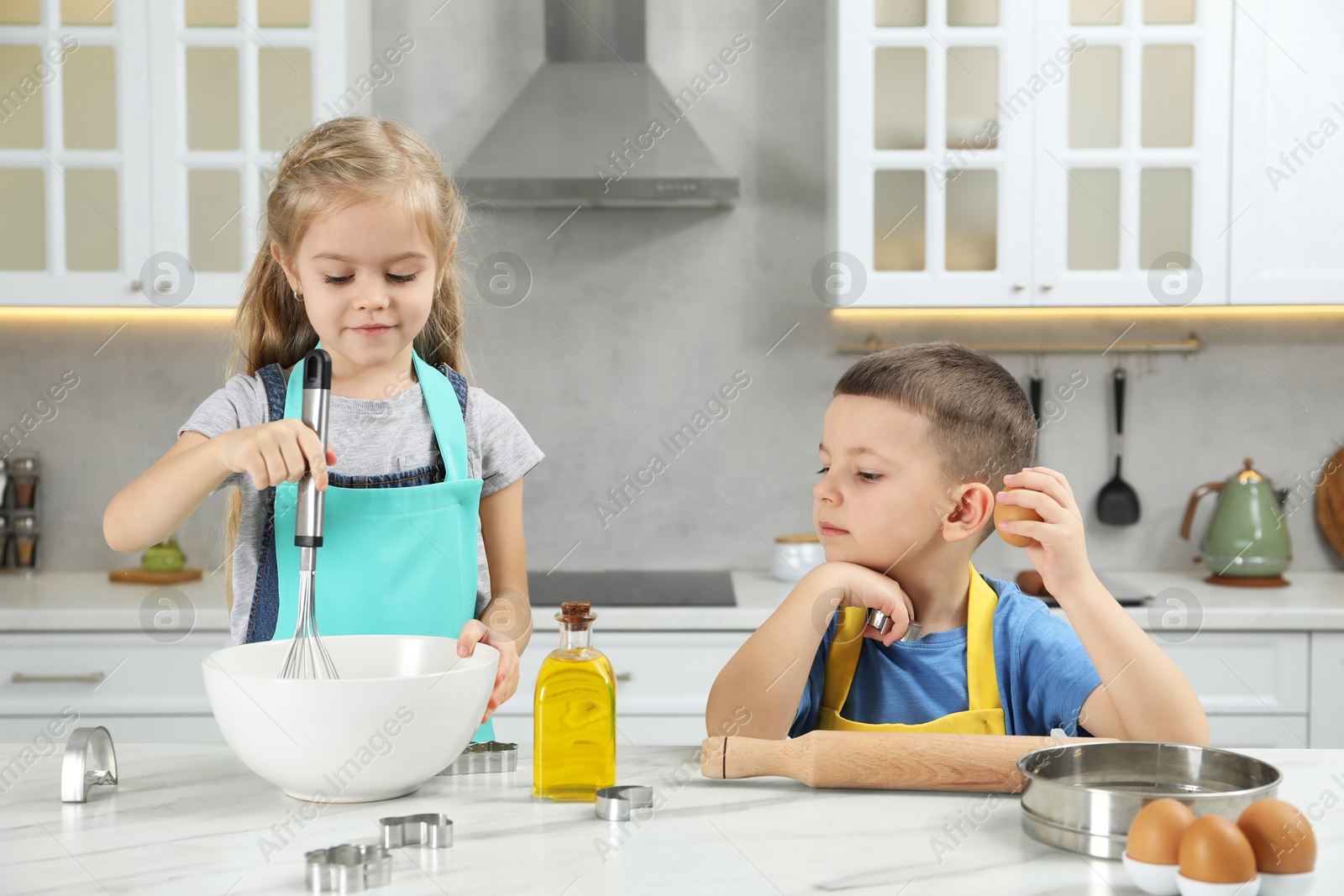 Photo of Little helpers. Children making dough for cookies in kitchen at home