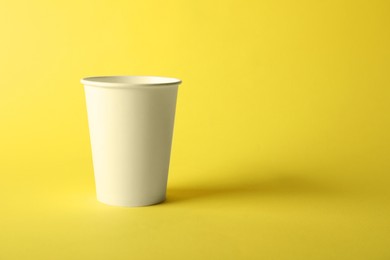 Photo of One paper cup on yellow background. Mockup for design