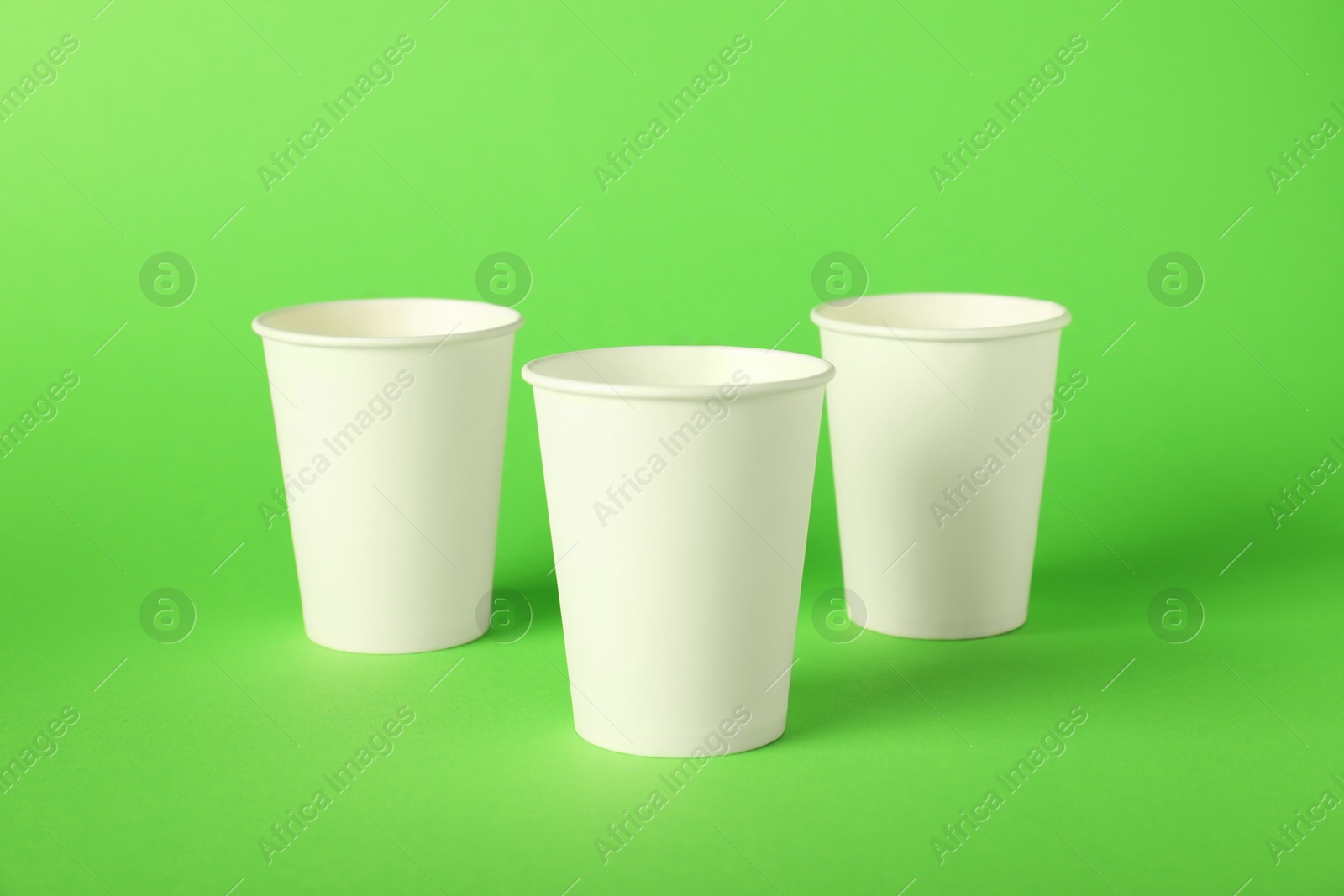 Paper cups on green background. Mockup for design Photo of Paper cups on green background. Mockup for design