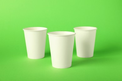 Photo of Paper cups on green background. Mockup for design