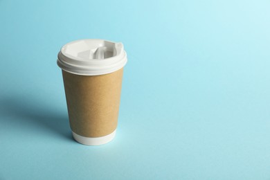 Photo of One paper cup on light blue background. Mockup for design
