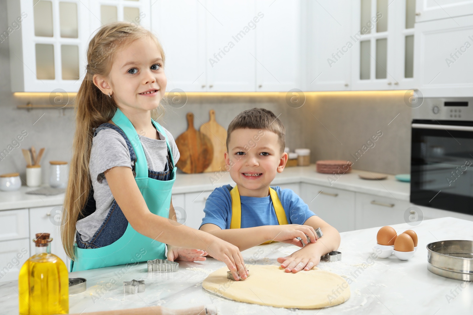 Photo of Little helpers. Children making cookies in kitchen at home