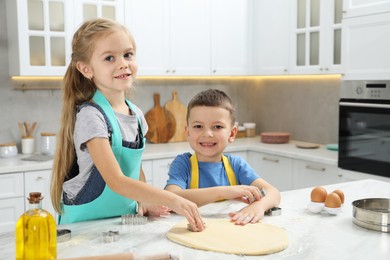 Photo of Little helpers. Children making cookies in kitchen at home