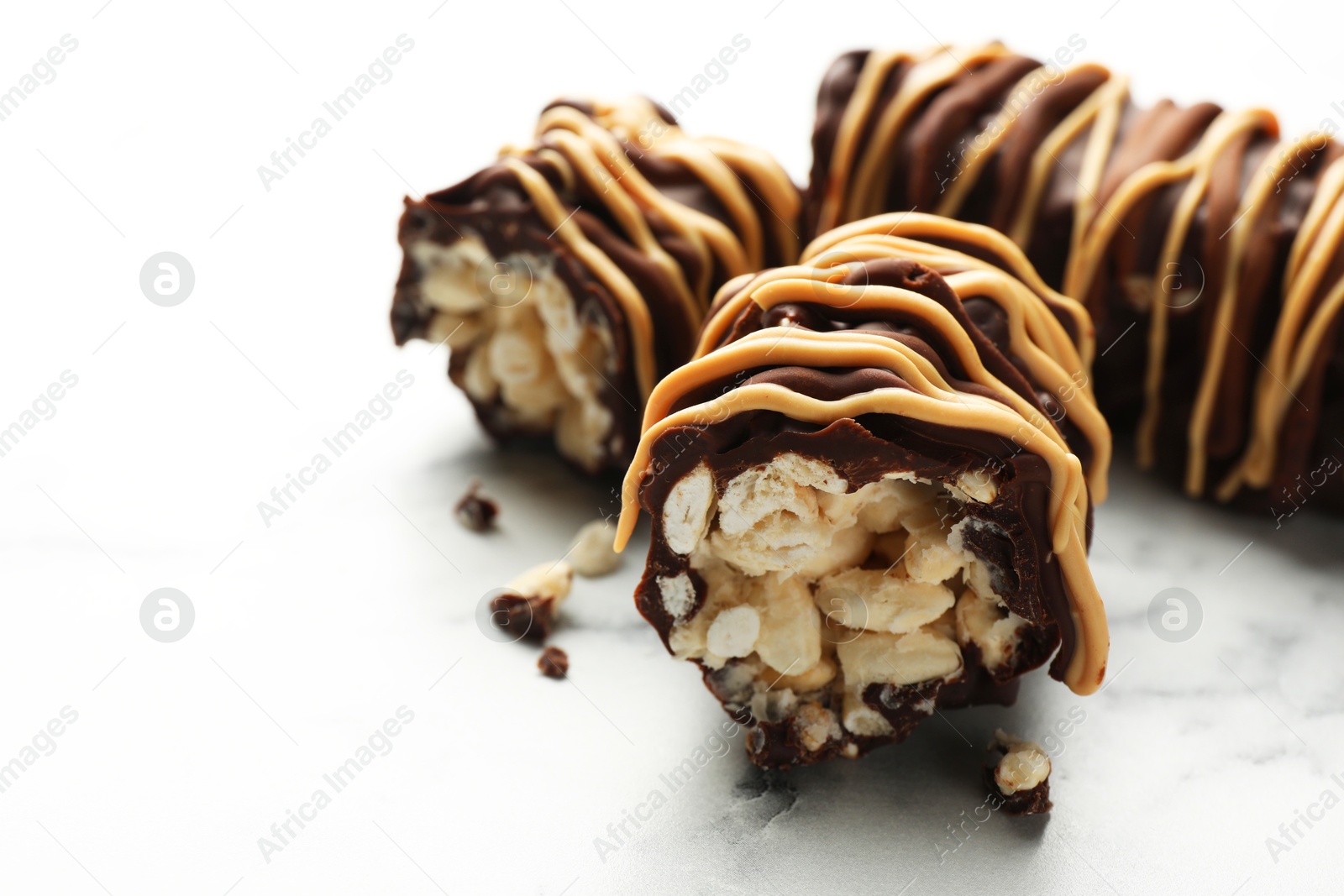 Photo of Delicious chocolate puffed rice bars on white marble table, closeup. Space for text