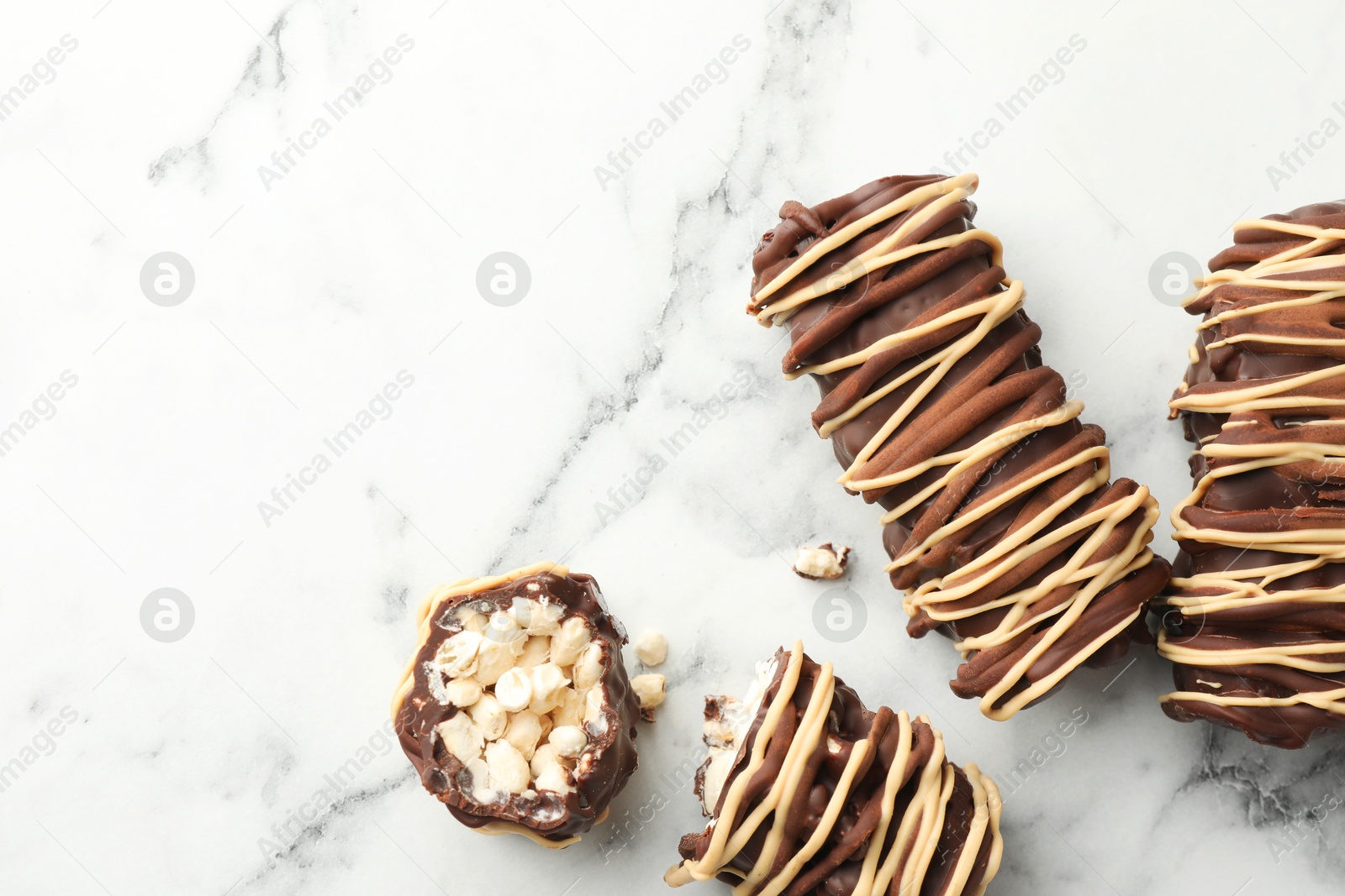 Photo of Delicious chocolate puffed rice bars on white marble table, flat lay. Space for text