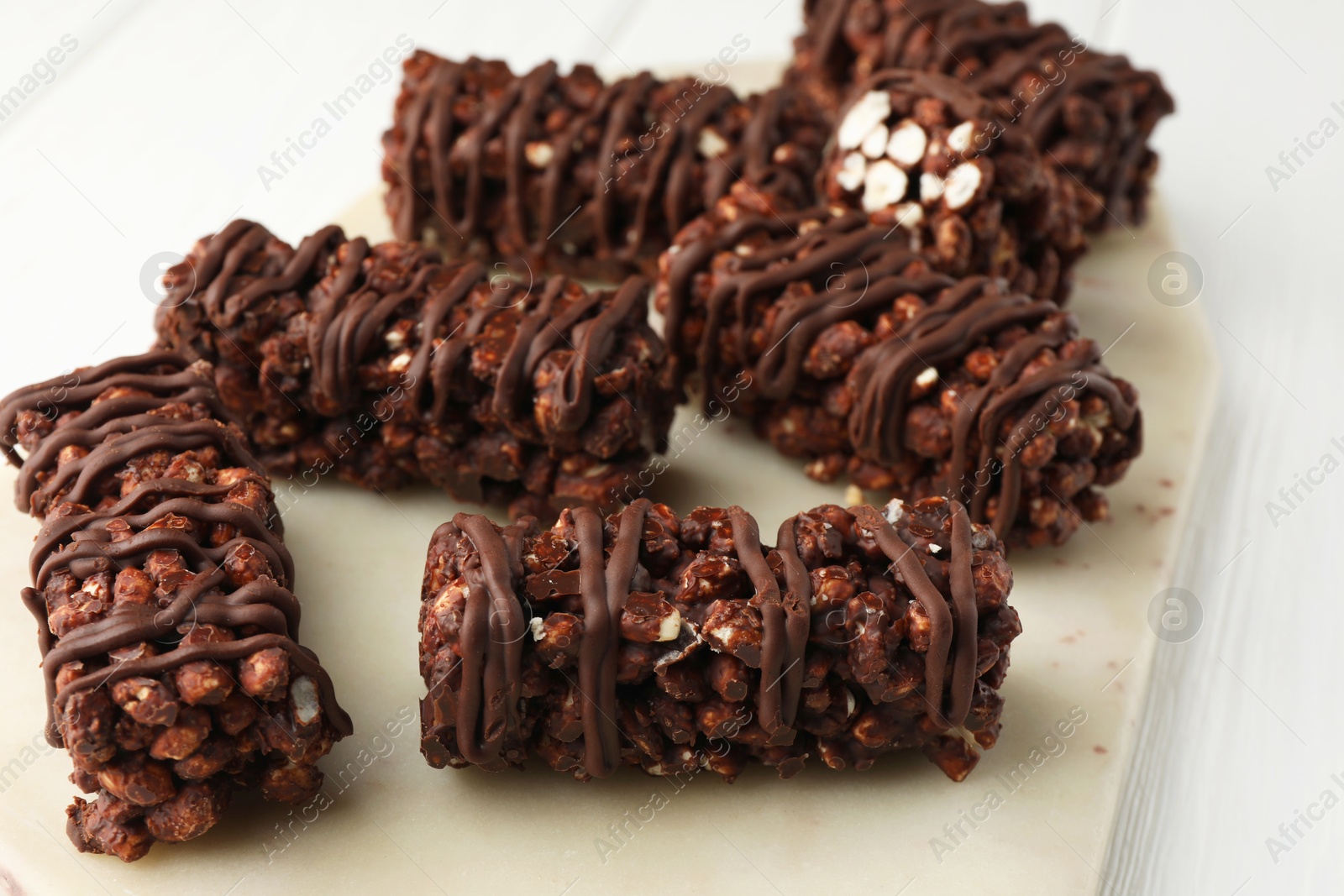 Photo of Delicious chocolate puffed rice bars on white wooden table, closeup