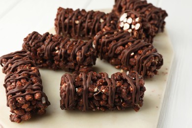 Photo of Delicious chocolate puffed rice bars on white wooden table, closeup